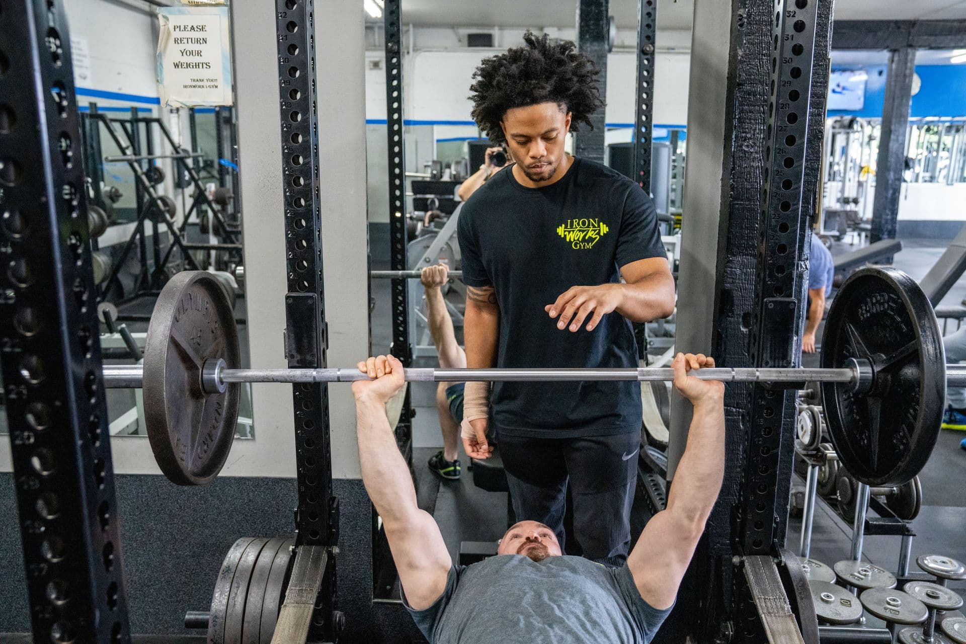 Member performing preacher curls at Iron Works Gym
